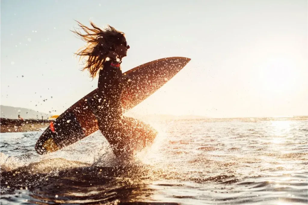 A woman surfing at sunset in Newport, RI, highlighting thrilling outdoor things to do in Newport RI.