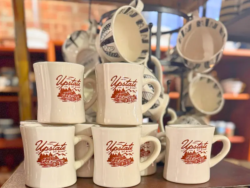 Upstate New York souvenir mugs displayed in a local shop.