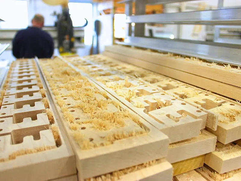 Wooden puzzle pieces being made during toy factory tour.