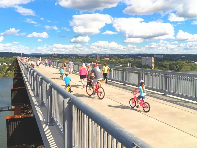 Families walking and biking across the Walkway Over the Hudson on a sunny summer day.