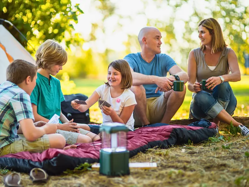 Family playing cards at the campsite... one of the fun things not to forget when camping with kids.