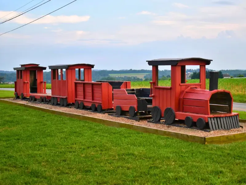 Red wooden train play structure on grass in Strasburg PA.