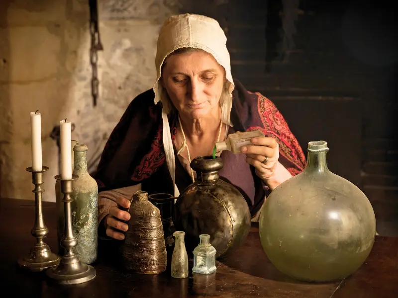 Woman reenacting potion brewing in a weird museum exhibit.