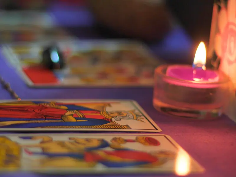 Tarot cards and candle in a dimly lit weird museum room.