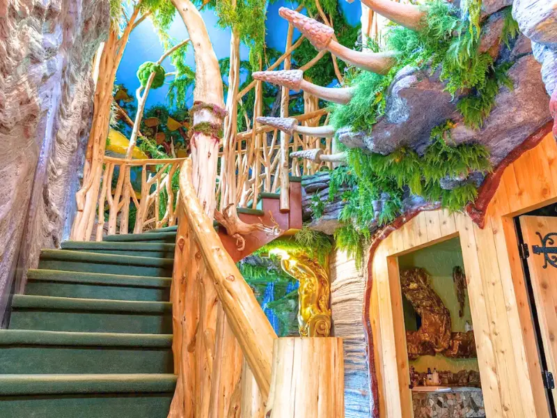 Rustic staircase wrapped in branches leading to a loft treehouse suite at The Roxbury Motel.