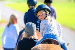 Little girl on trail ride during horseback riding family vacations in the Northeast.