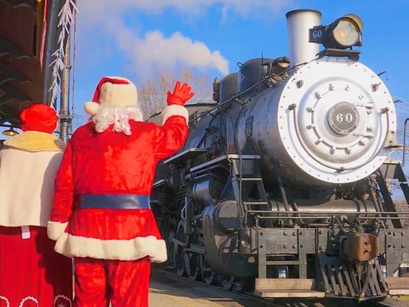 Santa and Mrs. Claus waving to a steam train at the Polar Express in New Jersey