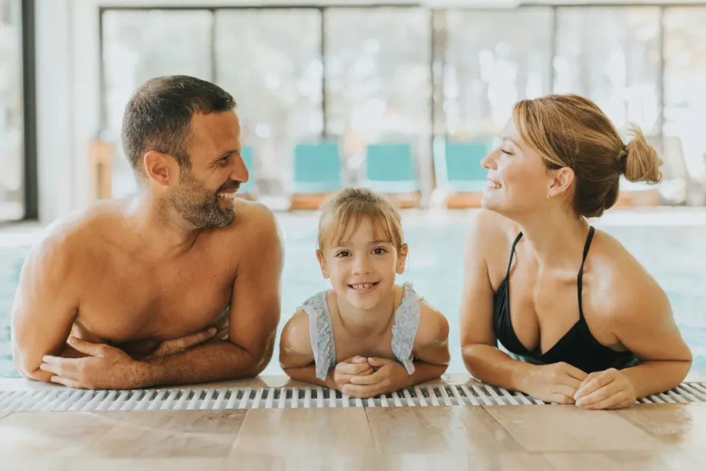 Family relaxing at the edge of an indoor pool during a Northeast vacation rental stay