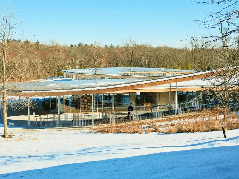 Grace Farms River Building with glass walls and curved roof surrounded by snow