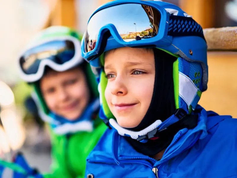 Two kids in ski helmets and goggles getting ready for spring skiing in Vermont
