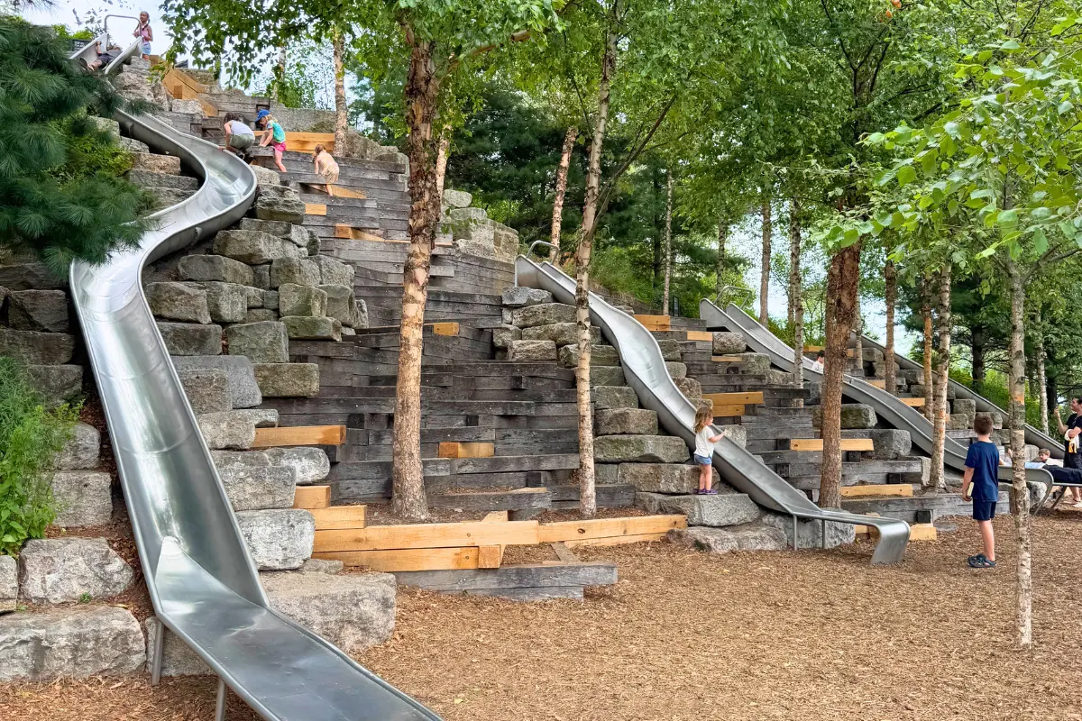 Kids climbing and sliding down the hillside slides at Slide Hill playground on Governors Island in New York City