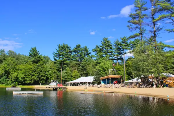 Sandy beach area and waterfront seating at The Sunset Tiki Bar in Westford with open space for kids
