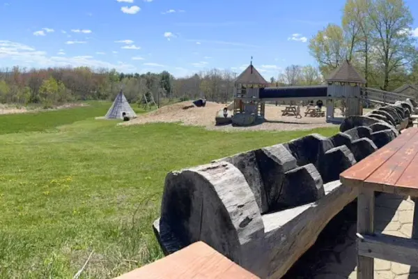 Open field and playground at Stone Cow Brewery in Barre with wooden structures and wide grassy space
